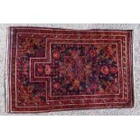 An Afghan hand knotted woollen rug, stylised floral decoration on a navy blue ground, 142cm x 88cm