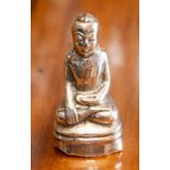 A Chinese white metal figure of a seated Buddha.