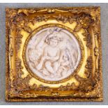 A framed reconstituted cast marble plaque, modern, modelled as three putti at leisure, set in a