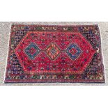 An early 20th Century hand knotted woollen rug, having geometrical motifs on a red ground, repeating