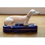 A Staffordshire greyhound pen stand, circa 1865, in typical recumbent pose and on dark blue gilt-