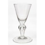 An English baluster wine glass, circa 1720-40, the funnel bowl above a baluster stem with teardrop