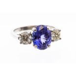 A tanzanite and diamond platinum ring, the claw set oval tanzanite measuring approx. 10mm x 7.8mm