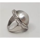 A large 18ct. white gold, diamond and mabe pearl dress ring, the ovoid mount set single large mabe