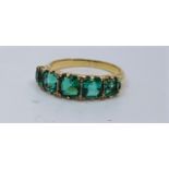 A precious yellow metal five stone emerald ring, set five graduated emerald cut emeralds, (total