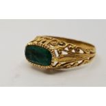 A 19th century yellow metal and emerald ring, set oval cut emerald to centre, with pierced scroll