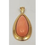 A large 18ct. gold and pink coral pendant, having pear shaped cabochon pink coral within similarly