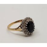 A 9ct. gold sapphire and diamond cluster ring, set central mixed oval cut sapphire surrounded by