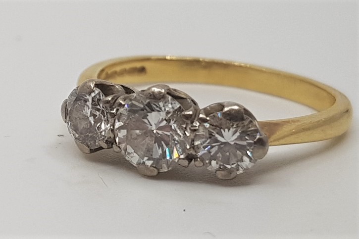 An 18ct. gold three stone diamond ring, set row of three graduated round brilliant cut diamonds (the