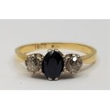 An 18ct. gold, sapphire and diamond ring, set mixed oval cut sapphire to centre flanked by single