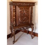 A mahogany drinks cabinet on stand, elaborately carved scrollwork throughout, retractable door