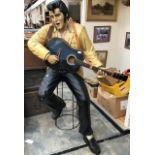A life size model of Elvis Presley playing an acoustic guitar