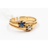 A sapphire and diamond 18ct gold cross over ring, each side claw set with a single sapphire and