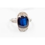 A sapphire and diamond 18ct gold ring, set to the centre with an cushion cut sapphire rubover set,