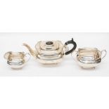 A George V silver three piece tea set, plain bodies with wavy rim on four stud feet, the teapot with