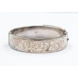 An Elizabeth II silver bangle, engraved with scrolling foliage, box clasp with safety chain,