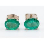 A pair of emerald and silver studs, comprising oval cut emeralds approx. 7x 5mm, claw settings