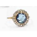 An Edwardian blue paste and diamond cluster ring, the central round cut stone approx. 9mm, rubover