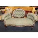 A mid Victorian walnut settee, having a deep buttoned back, buttoned sides, carved surround,