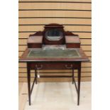 An Edwardian mahogany writing table, having a mirrored back, two hinged lidded sections, leather