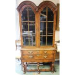 A Queen Anne style walnut glazed bookcase, the pediment with double domed top, the upper section