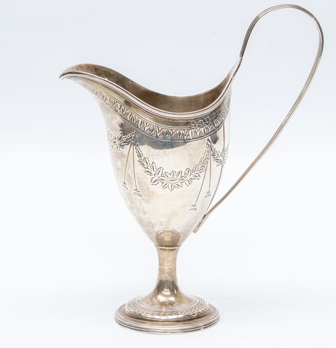A George III silver helmet shaped cream jug, the body bright-cut engraved with swag tied floral