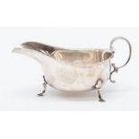 A George V silver oval sauceboat, wavy rim C-scroll handle on three spade feet, by Martin Hall &