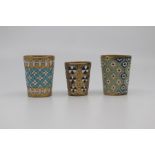Three Russian gilt and enamelled vodka cups, of tapering form and decorated with stylised flower