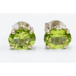 A pair of peridot and silver studs, comprising oval cut peridot approx. 7.5x 5.5mm, claw settings