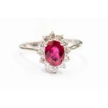 A ruby and diamond 18ct white gold ring, comprising a claw set oval ruby set to the centre within