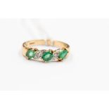 An emerald and diamond 9ct gold ring, set with three claw set emeralds with illusion set diamonds in