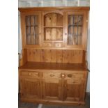 A contemporary solid pine dresser and rack, the upper section with two glazed doors and two drawers,