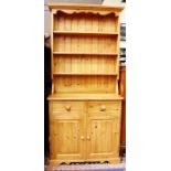 A traditional solid pine dresser and rack, the rack with fitted shelves, the base section with two