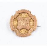 A 9ct rose gold badge, round form with raised engraved decoration, cartouche  initialled to front
