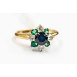 A sapphire, emerald and diamond cluster 18ct gold ring, comprising a central round cut sapphire claw