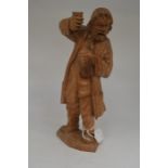 A Black Forest hand carved figure of a drunken man, standing with a glass in his right hand and a