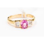 An 18ct yellow gold a pink sapphire and diamond ring, comprising a central claw set oval pink