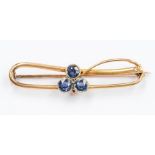 A 15ct gold mounted scrolling bar brooch with central Shamrock motif set three Sapphires each