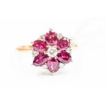 A ruby and diamond flower 18ct gold  cluster ring, comprising a central brilliant cut diamond with a