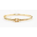 An 18ct gold Mappin & Webb bangle with knot detail to the front, to ridged decorative band,