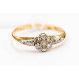 An Edwardian diamond set 18ct gold ring, floral cluster to the centre with diamond set shoulders,
