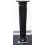 A 20th Century ebonised classical style single column torchere, the column turned and carved with