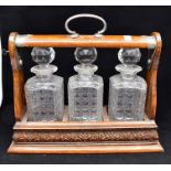 An early 20th Century three decanter Tantalus with key, carved oak case