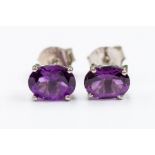 A pair of amethyst and silver studs, comprising oval cut amethysts approx. 7x 5mm, claw settings