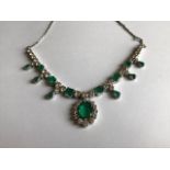 An emerald and diamond fringe necklace, the principal oval cut emerald drop within a border of