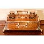 An early 20th Century oak and silver plate inkwell, twin inkwell moulded pen tray, base drawer,