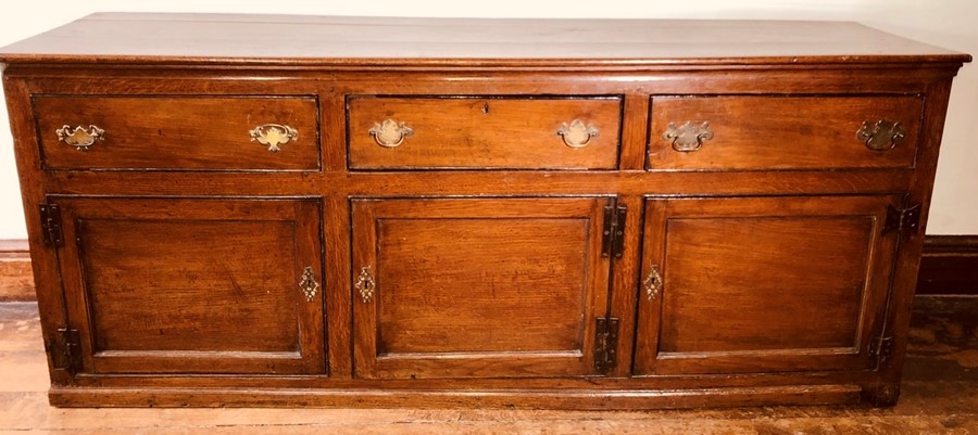 An early George III oak dresser base, circa 1760, rectangular top above moulded edge, fitted with