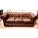A 20th Century dark brown leather chesterfield two seater sofa, raised on bun feet.
