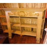 An early 20th century varnished pine fire surround, moulded dental pediment above baroque style