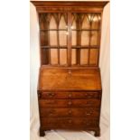 An early 19th Century late George III crossbanded oak glazed bookcase on bureau, circa 1820, moulded